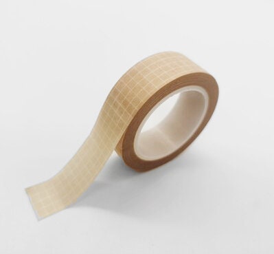 A roll of Minimal Grid Washi Tape in beige on a white surface.